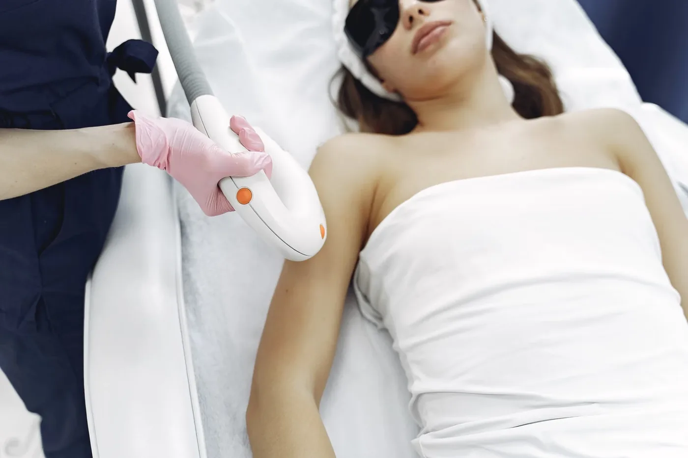 Clienta con gafas protectoras recibiendo un tratamiento de luz pulsada en el brazo.